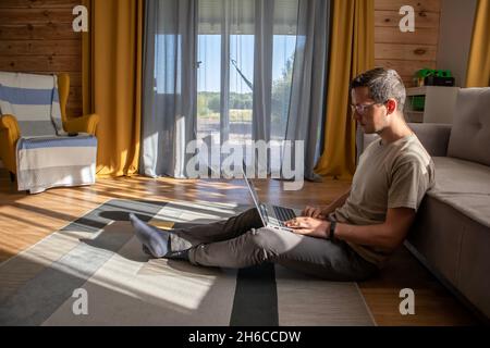 Comfortable work from home. A man is sitting and working on the floor Stock Photo