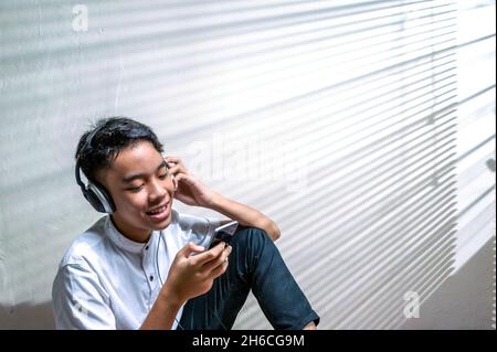 Indonesian male teenage listening music using headphone Stock Photo