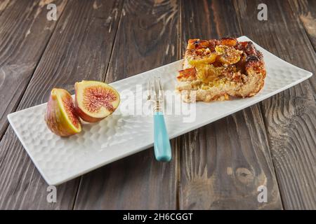 Clafoutis with figs and honey on white plate, on wooden background. French gourmet food Stock Photo