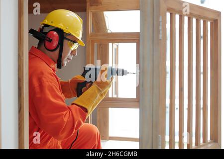 Side view of concentrated builder with drill using self-tapping screw when working with wood Stock Photo