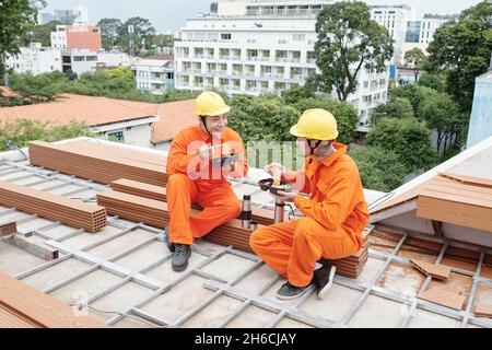 Positive roofing contractors having lunch together, they are eating noodle soup and discussing work Stock Photo