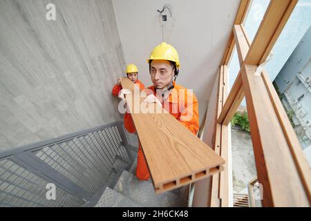 Serious construction workers carrying building materials to the upper floor of house Stock Photo