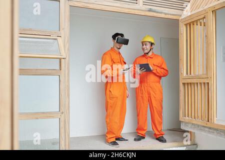 Positive contractors using virtual reality helment and application on tablet computer when renovating house Stock Photo