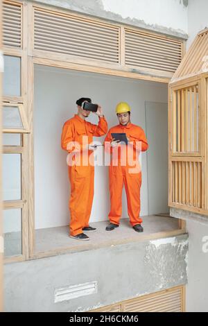 Contractors using virtual reality glasses for checking quality of thermal insulation in new house Stock Photo