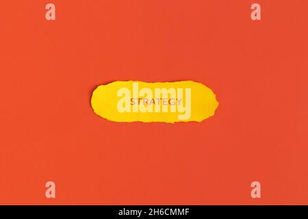 Yellow torn paper with text Strategy on red background Stock Photo