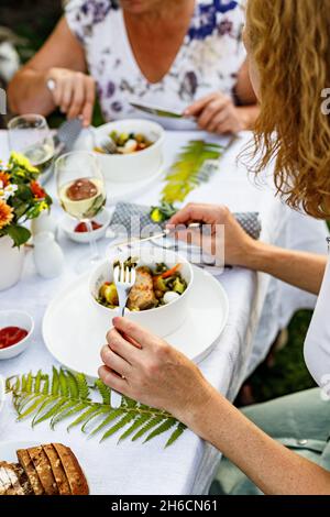 Family celebrations and food concept. The family is having dinner at a summer garden party. Table setting and decoration. Food and drinks. BBQ, vegeta Stock Photo