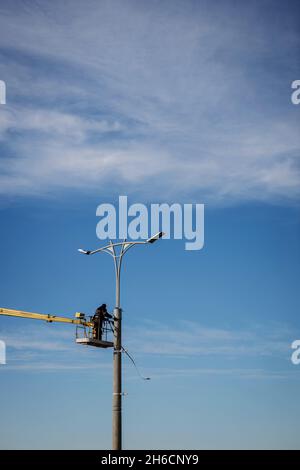 A worker in helmet is installing a new street lamp Stock Photo