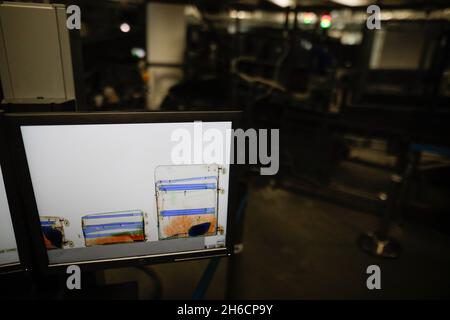 Shallow depth of field (selective focus) image with a screen showing luggages inside an x-ray scanning machine at an airport - airport security check. Stock Photo