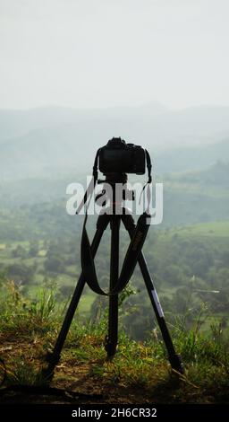 a camera mounted on a tripod pointing towards a landscape Stock Photo