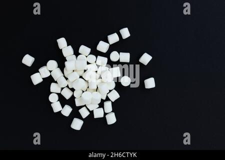 pile of marshmallows on black background, flat lay or top view, background or texture of white mini marshmallows, winter concept, sweet food Stock Photo