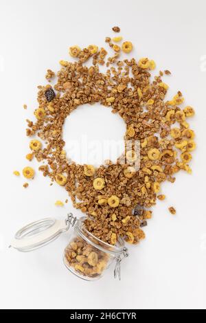 crunchy granola for breakfast, tasty granola poured out of glass jar forming frame for writing text on white background, concept healthy food Stock Photo