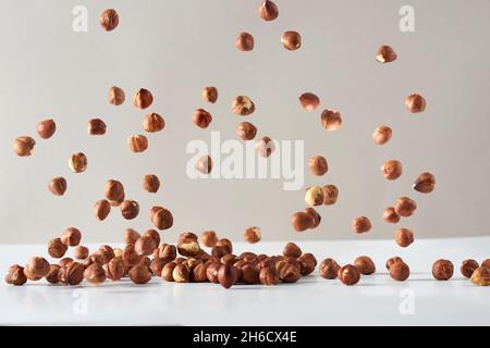 Flying hazelnut . Fresh raw hazelnut fall on a white background. Stock Photo