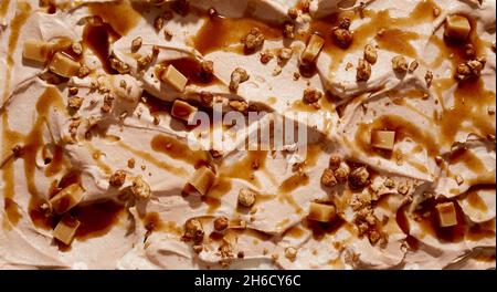 Gourmet caramel ice cream with chopped fresh walnuts and caramel candy in a wide angle panorama background texture for menu advertising Stock Photo