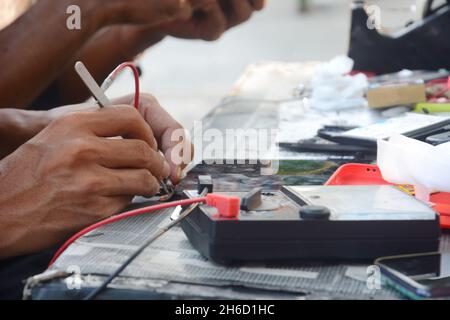 a technician is checking a cellphone using an avo meter Stock Photo