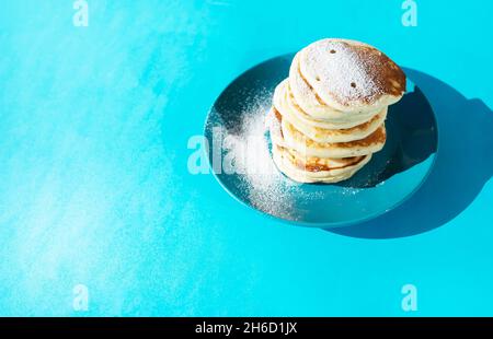 Pancakes Sprinkled with powdered sugar on a ceramic plate. Stock Photo
