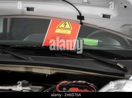 PRODUCTION - 12 November 2021, Hessen, Frankfurt/Main: A warning sign is stuck to the windscreen during work on an electric vehicle at the national performance competition of the German motor vehicle trade. Photo: Frank Rumpenhorst/dpa Stock Photo