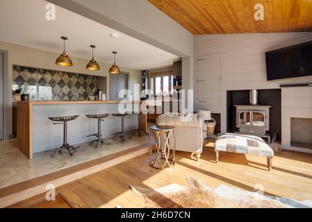 Suffolk, England - March 2018: Home interior kitchen family room showing breakfast bar with stools and seatinga area in front of wood burning stove Stock Photo