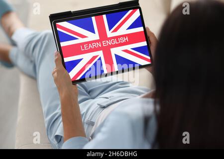 Woman learn english from home on sofa using tablet device Stock Photo