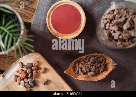 Top view of organic cacao beans on wooden table, cocoa nibs. Handmade healthy chocolate for a drink. Copy space. Cracked chocolate in cocoa pod. Flat Stock Photo