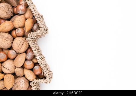 Top detail studio shot of basket full of mixed nuts isolated on white background with lot of free space to the right. Christmas concept. Stock Photo