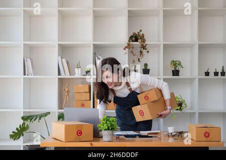Starting Small business entrepreneur SME freelance,Portrait young woman working at home office, BOX,smartphone,laptop, online, marketing, packaging