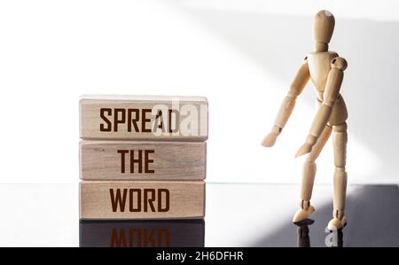 Spread the word written on a wooden block with a wooden doll. Spread out the text of the word on a white table, the concept. Stock Photo