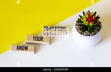There is a conceptual image on the wooden blocks. Text KNOW THAT YOUR COMPETITORS are doing well in business. White and yellow background with cactus