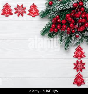 Christmas greeting card with holly and snowflakes. New year frame with festive decorations. Spruce branches and red berries. Template with copy space. Stock Photo