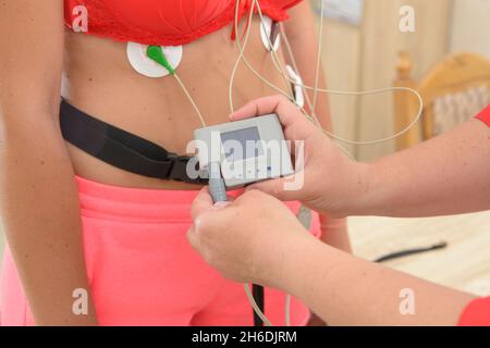 electrocardiography ECG leads for a portable heart monitor on an young woman patient. the nurse connects the ECG device to the patient Stock Photo