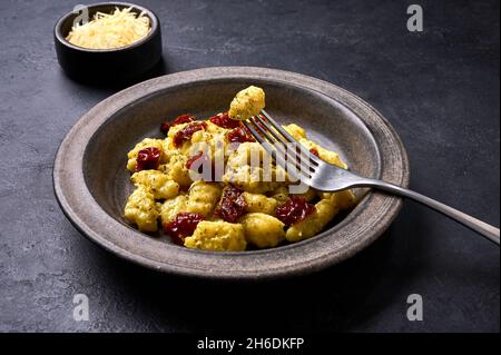 Traditional Italian potato gnocchi pricked on a fork lying on plate with dish. Close up, selective focus Stock Photo
