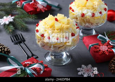 Festive salad with chicken, pineapple, cheese and eggs in portioned bowls on dark gray background Stock Photo