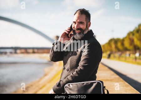 Businessman is sitting outdoor in the city and talking on phone Stock Photo