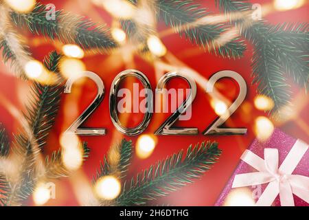 2022 New Year and Christmas celebration. Composition with numbers, blurry lights and gift box Stock Photo