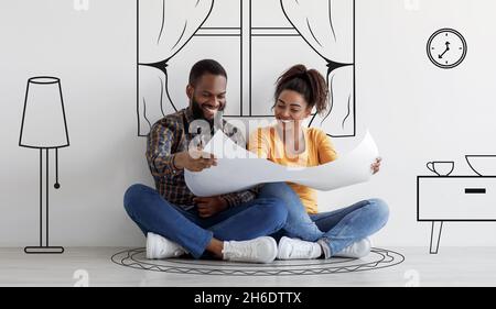 Cheerful black couple planning new house interior, holding blueprints Stock Photo