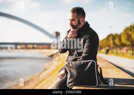 Businessman is sitting outdoor in the city. He is worried and anxious. Stock Photo