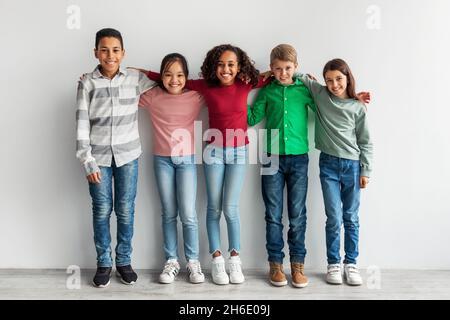 Group Of Happy Diverse Preteen Children Embracing Over Gray Background Stock Photo