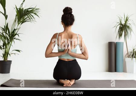Rear View Of Young Woman Practicing Yoga, Making Reverse Prayer Pose Stock Photo