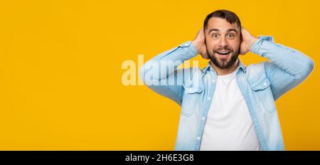 Happy surprised adult caucasian male holding hands behind head, look at camera Stock Photo
