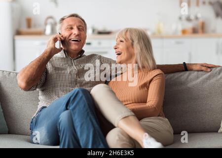 Happy Senior Couple Talking On Phone And Laughing At Home Stock Photo
