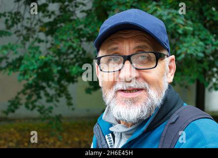 portrait of an elderly man with a beard and glasses. outdoor closeup Stock Photo