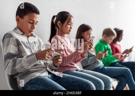 Group Of Diverse Preteen Children Using Smartphones Over Gray Background Stock Photo