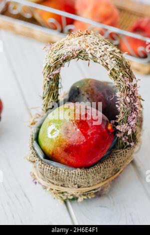 Ripe mango in a basket over a white wooden background Stock Photo