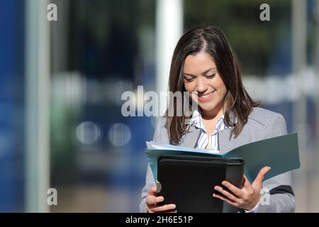 Happy executive reading paper report walking in the street a sunny day Stock Photo