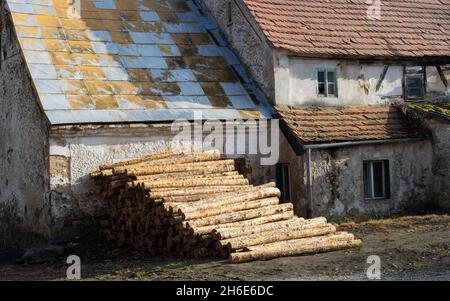 Old and destroyed rural buildings, house plus pile of wood. Destroyed historic farmstead Stock Photo
