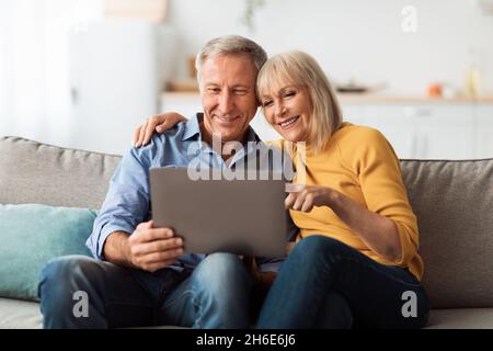Happy Senior Couple Using Laptop Browsing Internet Together At Home Stock Photo