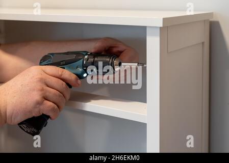 Man putting together self assembly furniture using a cordless screwdriver Stock Photo