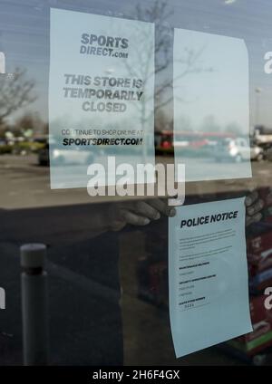 A staff member places a notice in the window of Sports Direct in