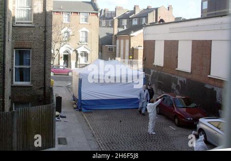 A police forensics officer attends the scene in Kilburn, north London, following the discovery of a body wrapped in sheets. Officers were called to the scene at 7.10am, after a member of the public made the discovery behind some shops. Stock Photo