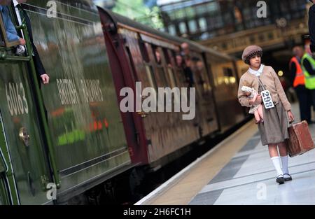 A steam train recreating the journey of hundreds of child evacuees, rescued from the Nazi's by a man dubbed Britain's Oscar Schindler, arrived at Liverpool Street station in London today. Seventy years after Sir Nicholas Winton organised for 669 Jewish children to travel from Prague to London to escape concentration camps, some of the survivors retraced their journey. Sir Nicholas, who celebrated his 100th birthday in May, was at the Station to see the steam train arrive. A young girl dressed as a refugee from World War Two walks past The Winton Train Stock Photo