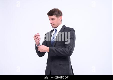 Portrait of elegant young caucasian handsome businessman in formal suit standing Isolated on white background in studio. Straightening cufflinks Stock Photo